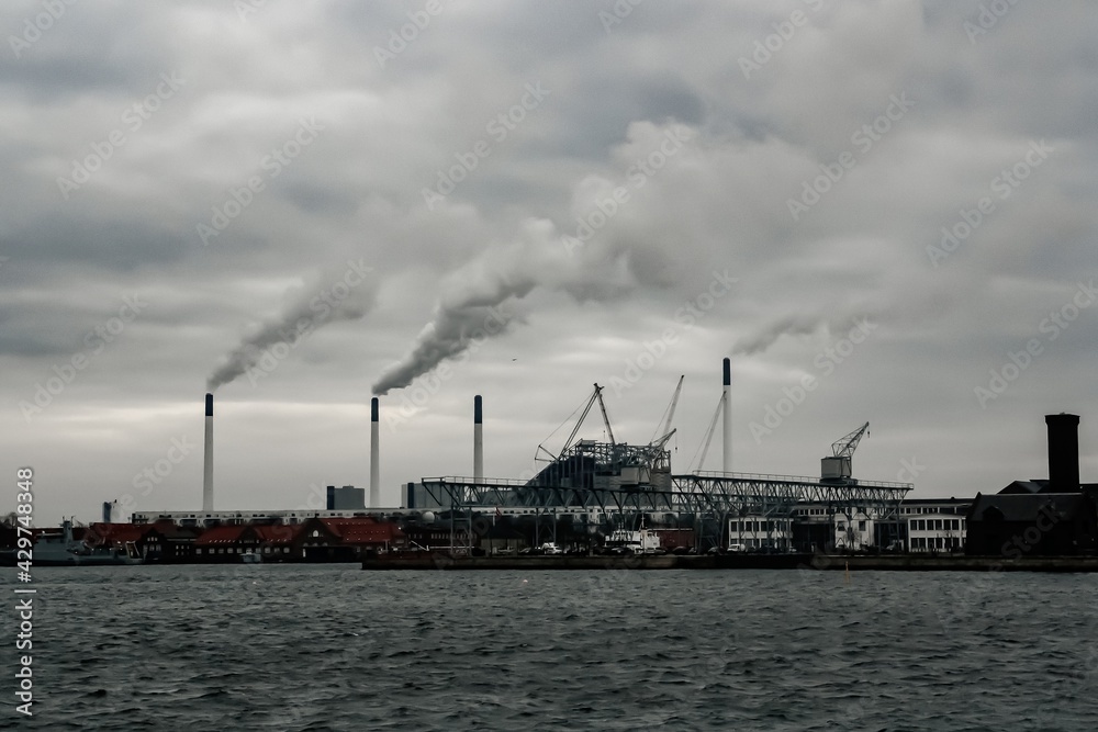 Puerto industrial de Copenhague con sus chimeneas humeantes en un día nublado de invierno. La zona industrial y comercial de Copenhague a pleno funcionamiento en un día laborable. Dinamarca. Puerto industrial de Copenhague con sus chimeneas humeantes en un día nublado de invierno. La zona industrial y comercial de Copenhague a pleno funcionamiento en un día laborable. Dinamarca.