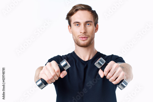 cute young man with dumbbells in hands goes in for sports on white background cropped view