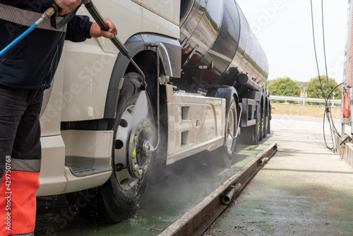 Fotografie Tank truck driver cleaning the exterior of the vehicle.