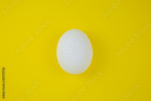 White egg on the yellow background. Copy space. Minimalism, original and creative photo. Beautiful wallpaper. Easter holidays.
