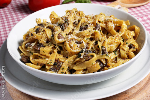 Gustoso piatto di tagliatelle con sugo ai funghi su tavola apparecchiata per il pranzo.
