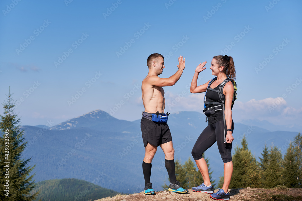 Good friends runners clapping each other's hands when they reached top of mountain hill while extreme jogging. Active run by mountain trails and lawns in summer holiday. Good friends runners clapping each other's hands when they reached top of mountain hill while extreme jogging. Active run by mountain trails and lawns in summer holiday.