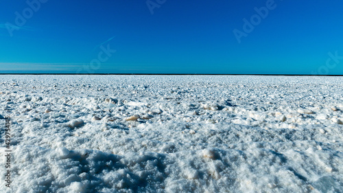winter landscape by the sea, ice pieces of different sizes, sea horizon in the distance, blue sky