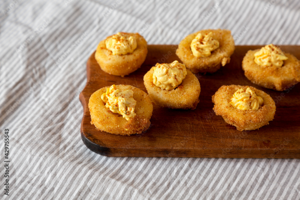 Homemade Deep-fried Deviled Eggs with Paprika on a rustic wooden board, side view. Copy space.