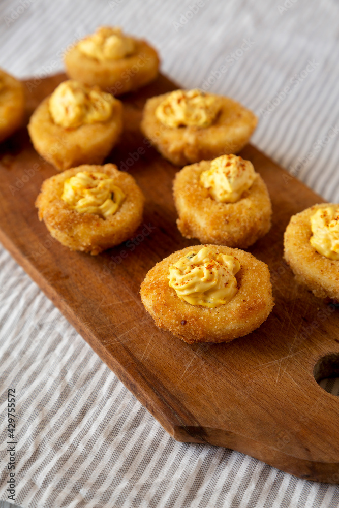 Homemade Deep-fried Deviled Eggs with Paprika on a rustic wooden board, low angle view. Homemade Deep-fried Deviled Eggs with Paprika on a rustic wooden board, low angle view.