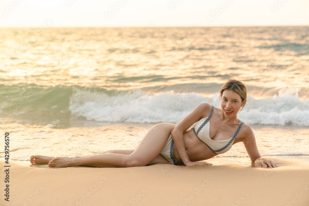 Woman in bikini lying down on sand,  relaxing sunbathing.