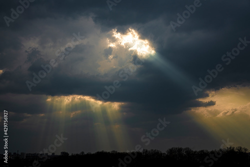 Dark sky with clouds, through which the rays of the sun break through