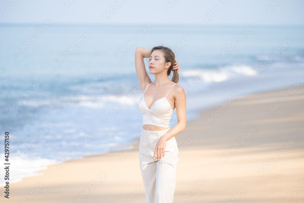 Happy young woman relax on the beach, arms raised up to sky.