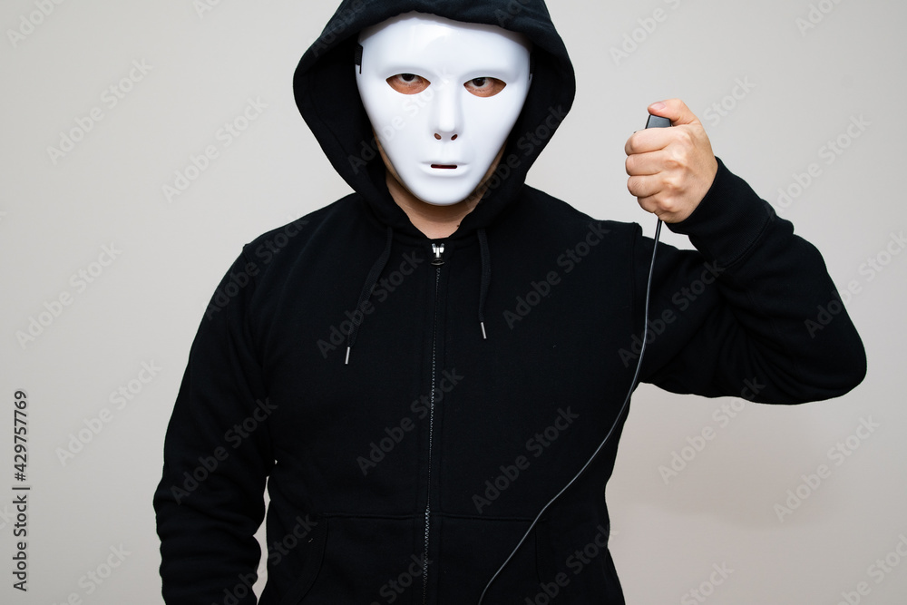 Hacker with anonymous mask holding a triggering device Hacker with anonymous mask holding a triggering device