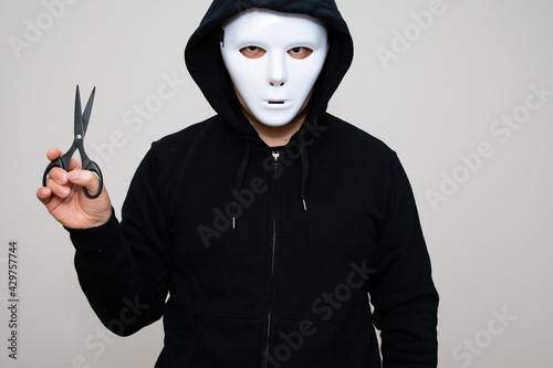 Hacker with anonymous mask holding a pair of scissors
