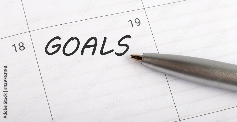 Text GOALS written on calendar planner to remind you an important appointment with a pen on isolated white background. Text GOALS written on calendar planner to remind you an important appointment with a pen on isolated white background.