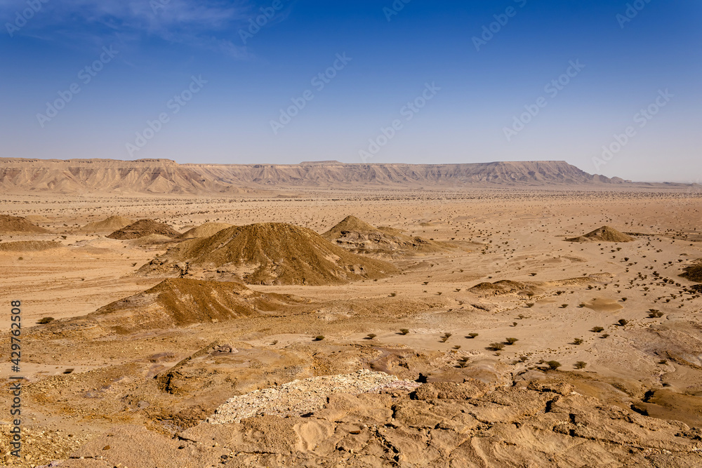 A desert landscape viewed from the Natural Arch of Riyadh. A plain surrounded by the mountain ridge - a Martian-like landscape.