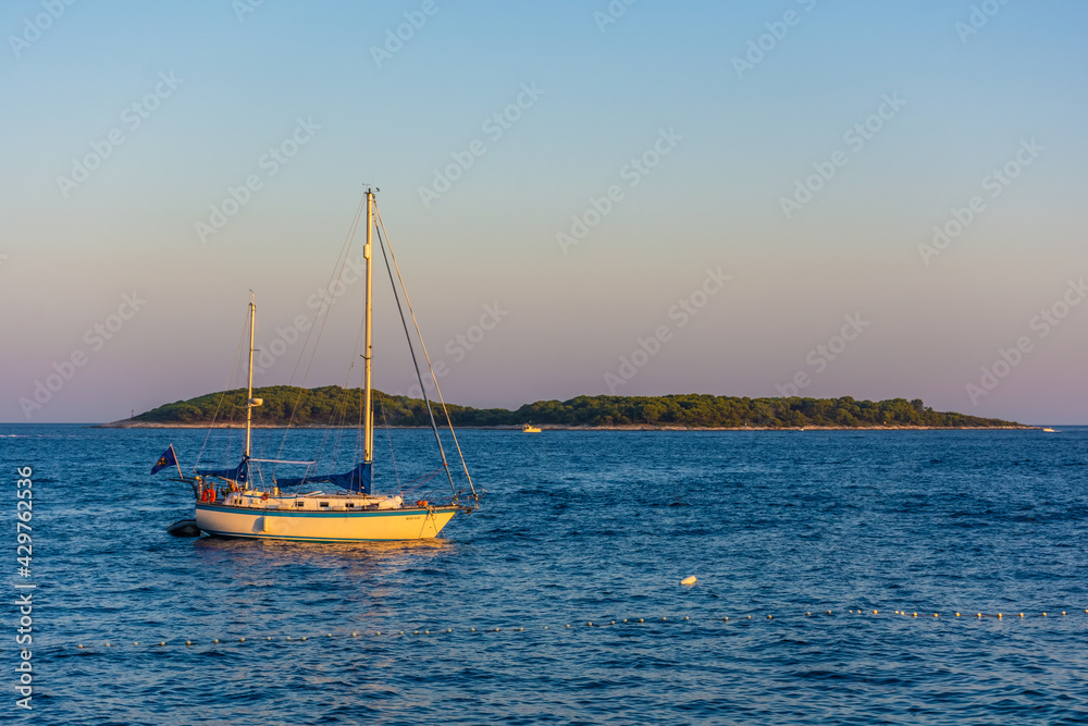 Fototapeta premium View of a boat sailing toward the Pakleni Islands from Hvar at sunset, Croatia