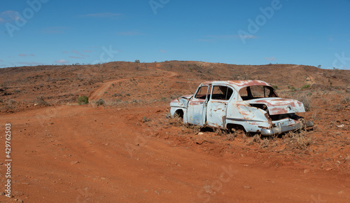 The rusted abandoned wreck of an old car in a remote area of Australian Outback on a rural dirt road near Fowlers Gap, NSW