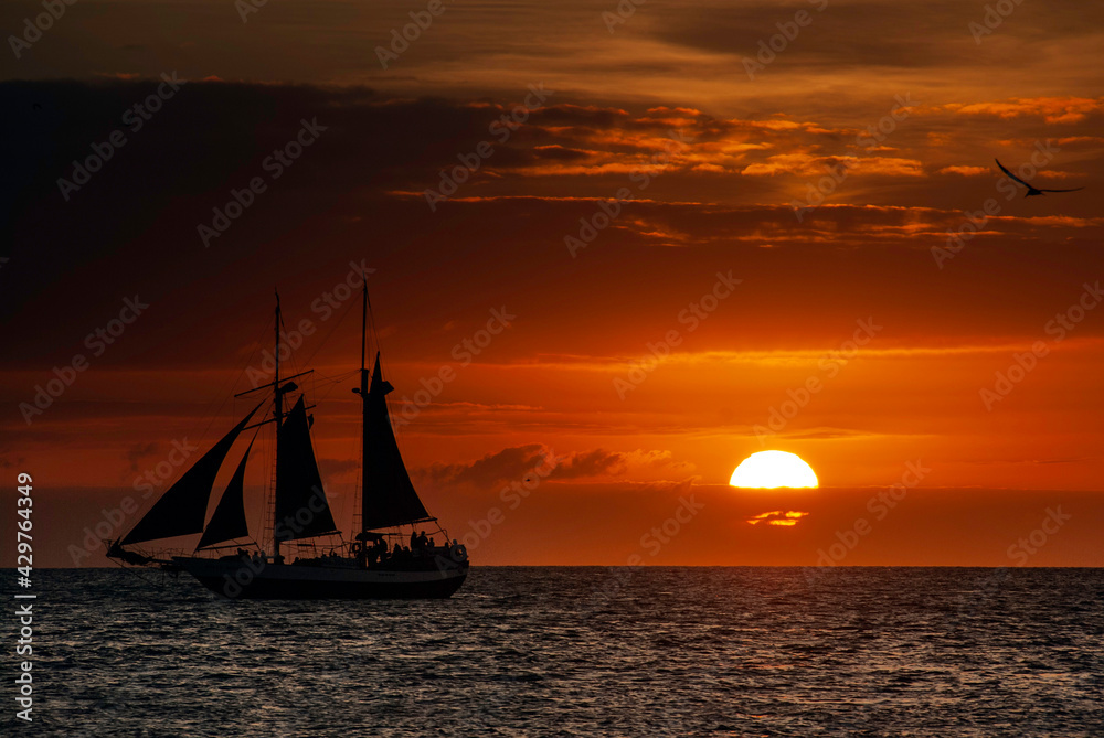 Silhouette of a sailing boat in full sail at sunset