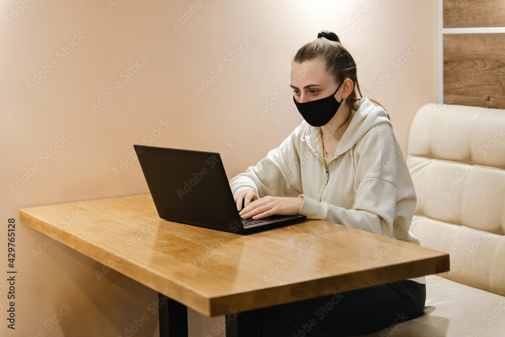 young girl in medical mask work on laptop in cafe young girl in medical mask work on laptop in cafe