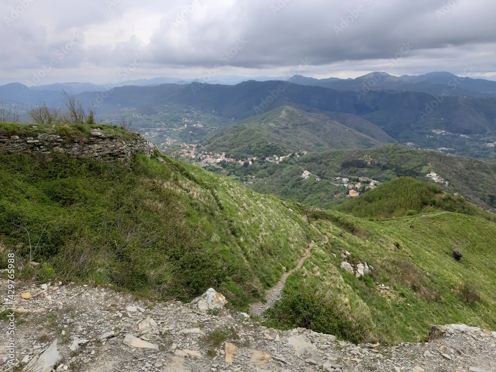 Discovering the mountains around Genoa. Panoramic view to the city. Grey sky in the background. First green leaves in spring. Discovering the mountains around Genoa. Panoramic view to the city. Grey sky in the background. First green leaves in spring.