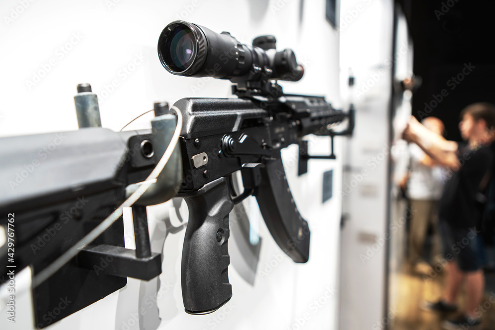 A rifle with a telescopic sight on the stand of an arms store. Trade and export of firearms to different countries. Selective focus