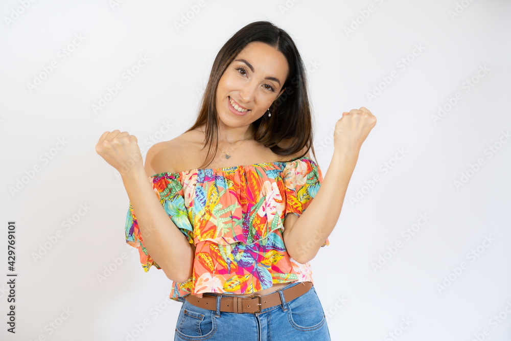 Young woman very happy and excited making winner gesture with raised arms isolated over white background Young woman very happy and excited making winner gesture with raised arms isolated over white background