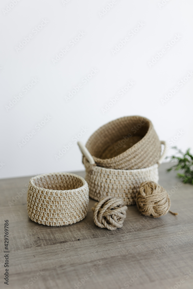 Handmade home decor made from organic jute fiber. wicker jute baskets on a wooden table. two balls of jute fiber and rope. the concept of home decor and comfort in the eco style.