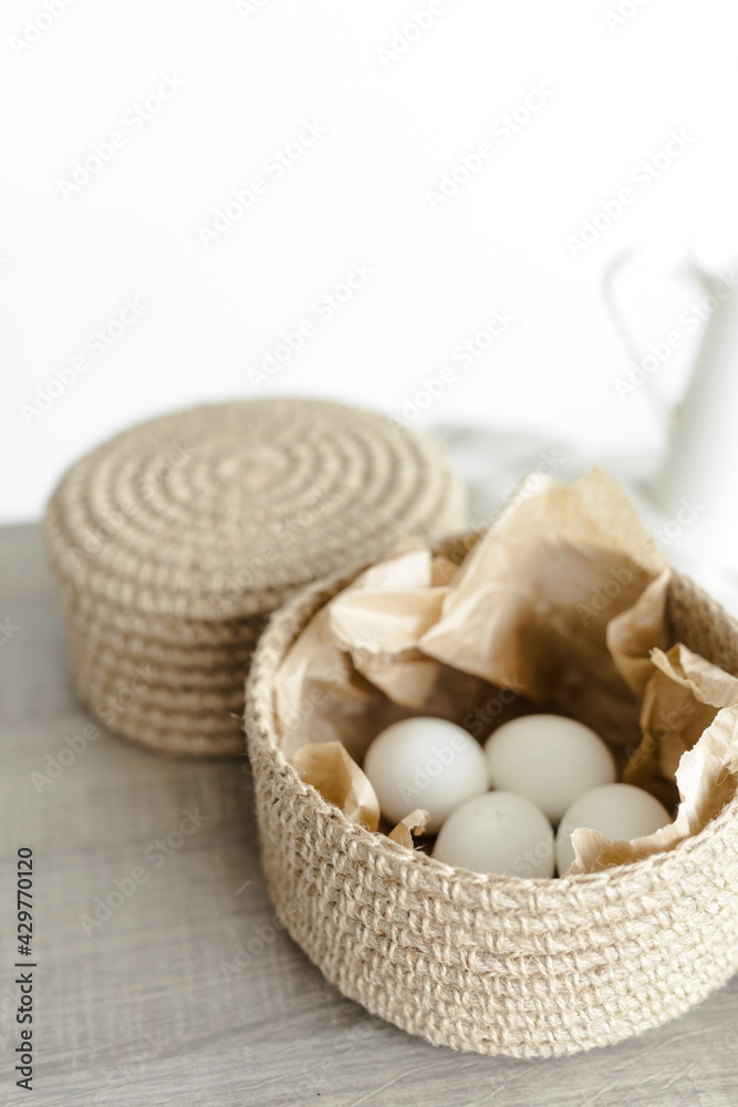 Handmade home decor made from organic jute fiber. Two wicker jute baskets are placed on a wooden table. White chicken eggs in a basket. The concept of Easter decor. Handmade home decor made from organic jute fiber. Two wicker jute baskets are placed on a wooden table. White chicken eggs in a basket. The concept of Easter decor.