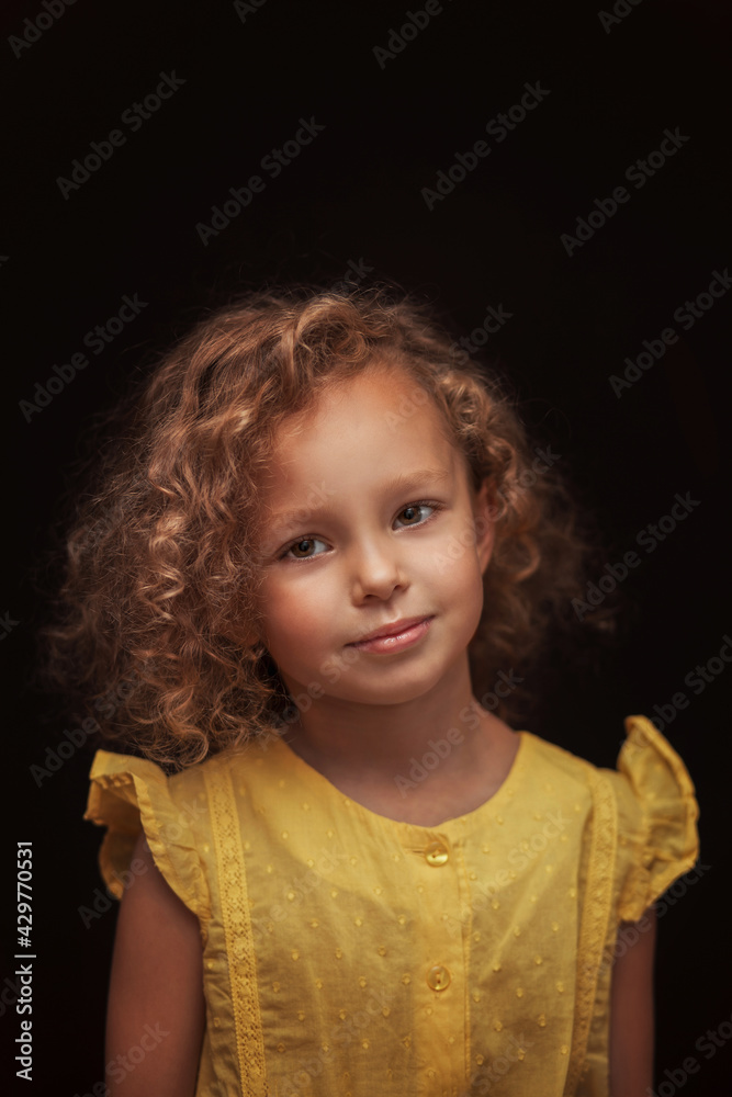 Portrait of a smiling beautiful girl with curly hair on a black background