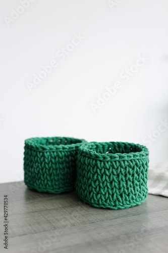 round baskets of green color on the table woven from knitwear on a white background