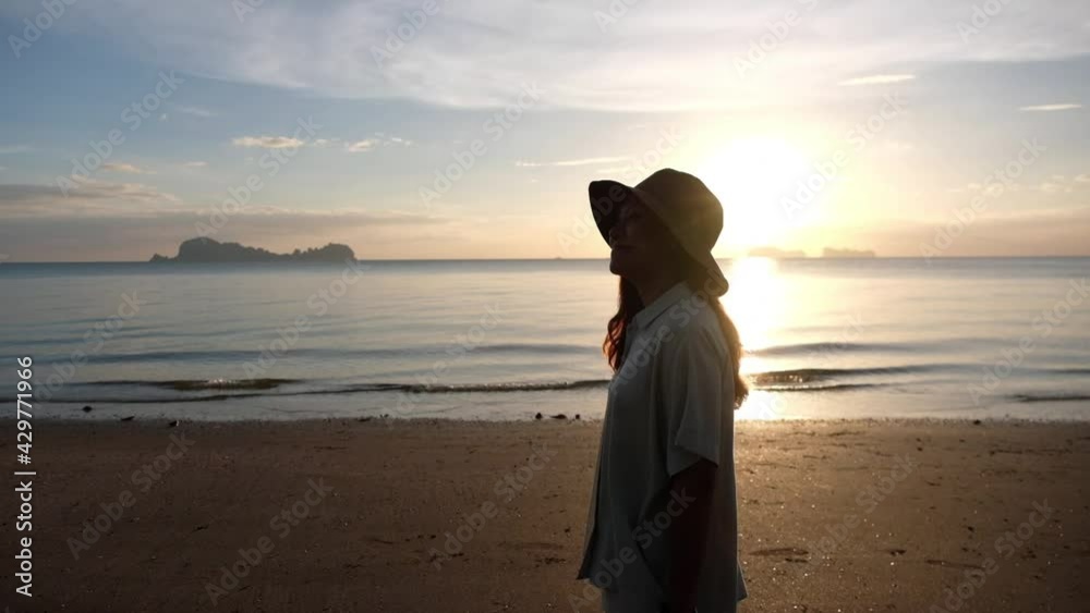 Slow motion of a young woman strolling on the beach before sunset Slow motion of a young woman strolling on the beach before sunset