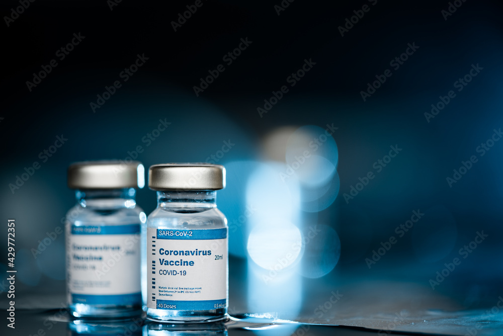 Two Covid-19 vaccine vials on blue background to inject people at risk. Two Covid-19 vaccine vials on blue background to inject people at risk.