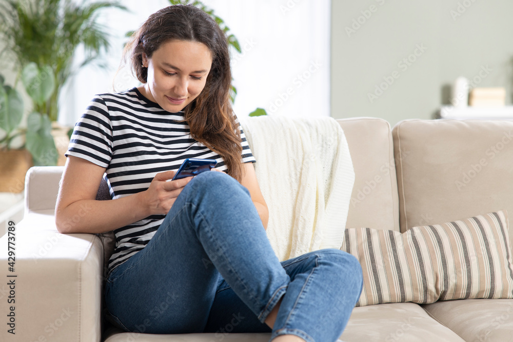 Fototapeta premium Young woman using phone at home