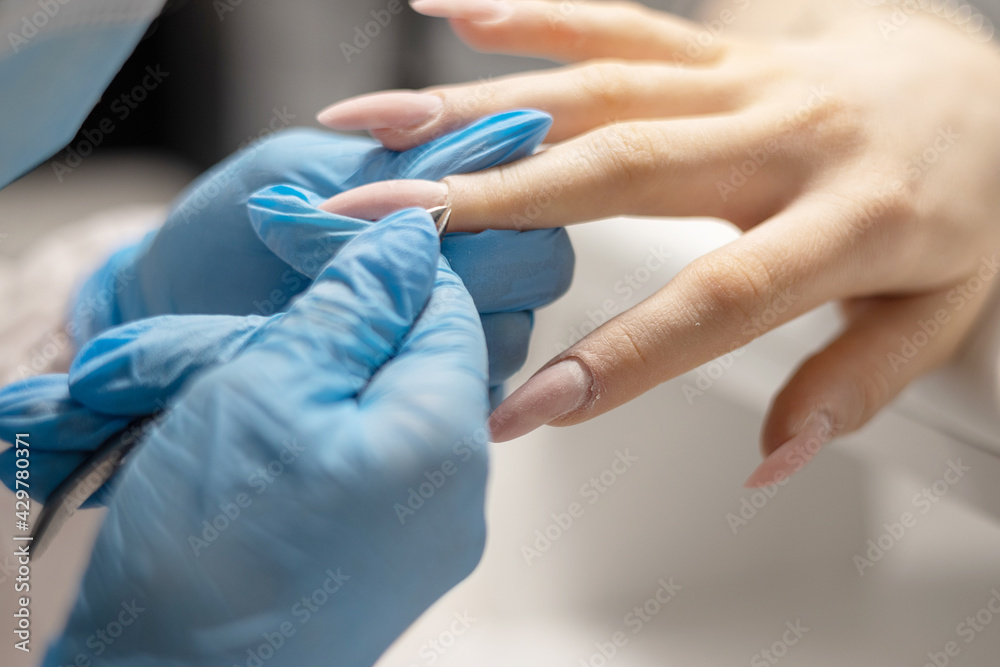 process of manicure in the salon on long nails, cutting the cuticle with a special tool