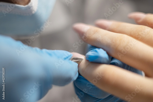 process of manicure in the salon on long nails, cutting the cuticle with a special tool