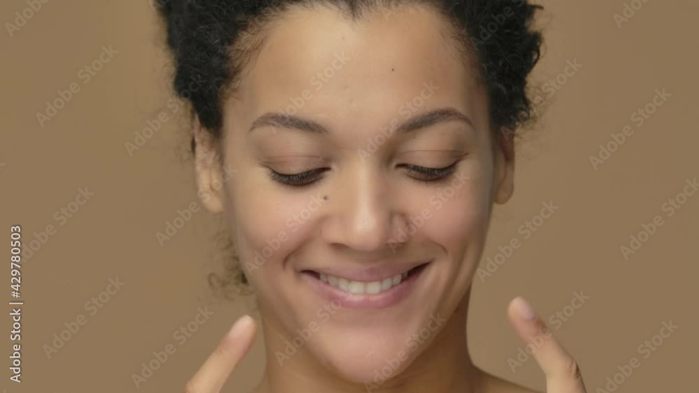 Beauty portrait of young African American woman pointing up hand for something then nods and shows thumb up. Black female posing on brown studio background. Close up. Slow motion ready, 4K at 59.94fps Beauty portrait of young African American woman pointing up hand for something then nods and shows thumb up. Black female posing on brown studio background. Close up. Slow motion ready, 4K at 59.94fps