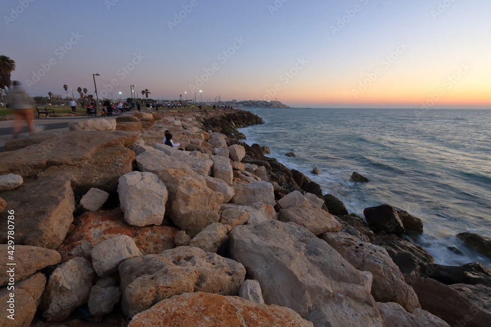 sunset on the sea, rocky stony shore in Tel Aviv, Israel