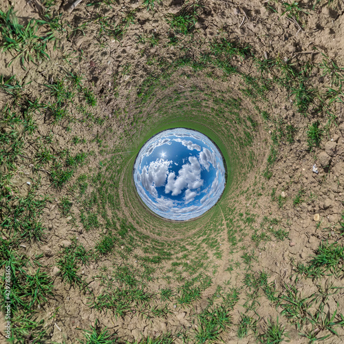 blue sky ball in middle of swirling green field. Inversion of tiny planet transformation of spherical panorama 360 degrees. Curvature of space.