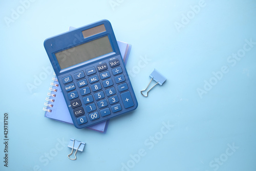 Close up of blue calculator and notepad on color background  photo