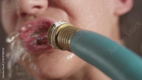 Close up shot of teen boy blasted in the face by a garden hose