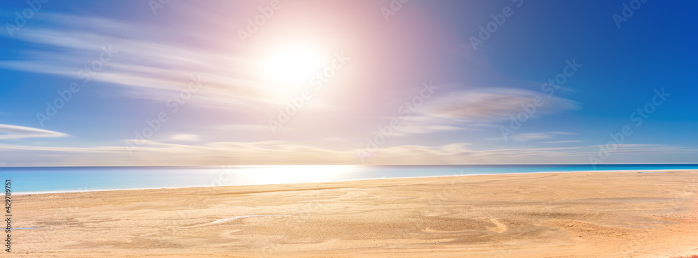 Panorama of a sandy beach with yellow sand and blue sea and sun