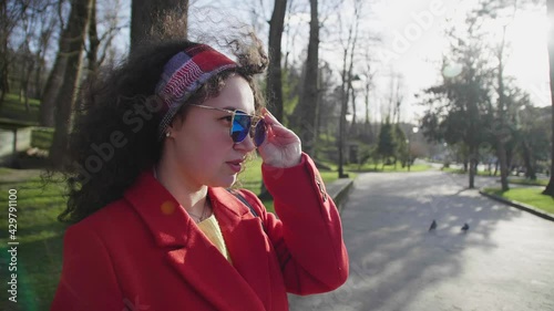 Pretty smiling curly woman in stylish look confidently sunglasses