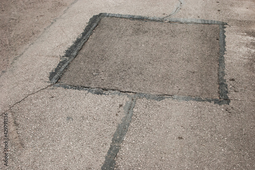 Cracked asphalt road surface and repair patch closeup