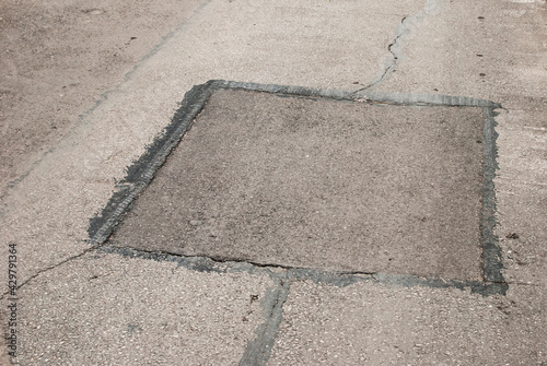 Cracked asphalt road surface and repair patch closeup photo