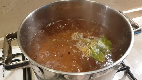 A metal saucepan on a gas stove. Boiling water with bay leaf, peppercorns and spices