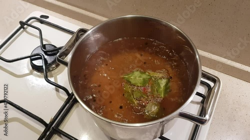 A metal saucepan on a gas stove. Boiling water with bay leaf, peppercorns and spices