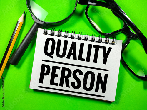 Selective focus.Text QUALITY PERSON with glasses,pencil and magnifying glass on green background.Laboratory concept.