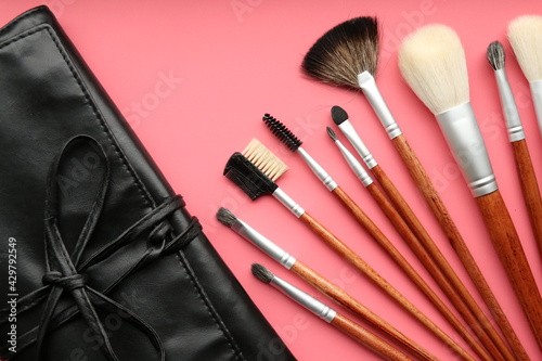 Top view of case and makeup brushes set on pink background 