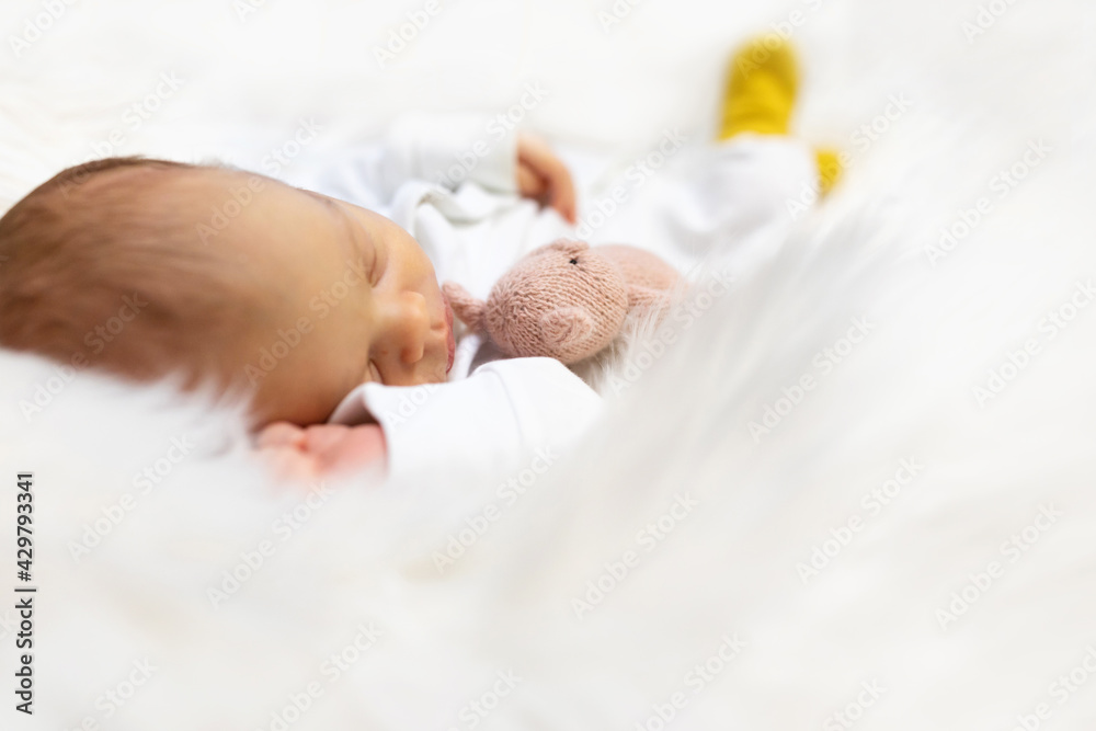 Adorable newborn one week age in white bedroom. Newborn child relaxing