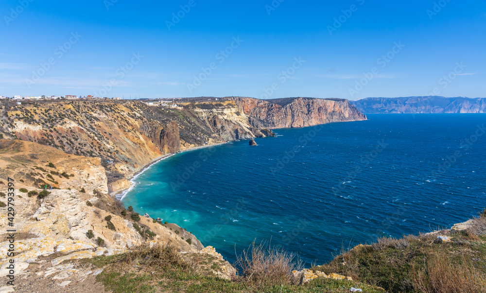 View of the Black Sea from Cape Fiolent in sunny weather. Blue sea water, blue sky contrasts with yellow coastal rocks