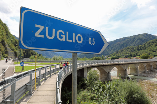 road sign with directions to reach the small village called ZUGLIO in Italy through the long bridge photo