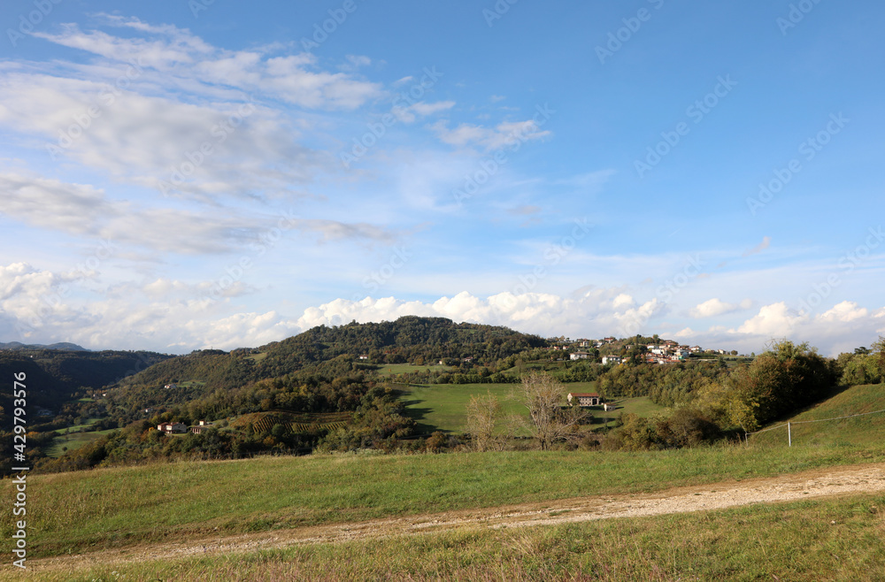 landscape with hills and fields and clouds in the clear sky