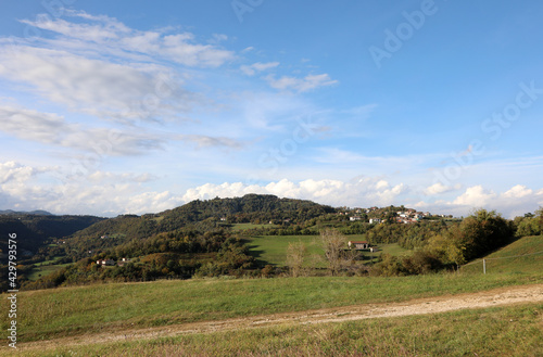 landscape with hills and fields and clouds in the clear sky